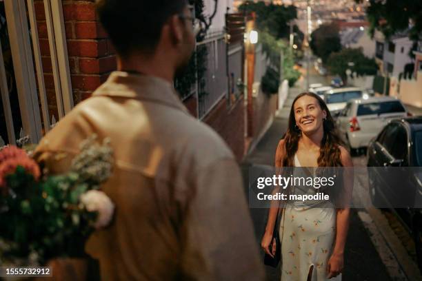 smiling young woman meeting a man with flowers before a date - restarting stock pictures, royalty-free photos & images