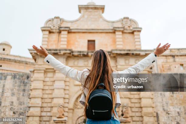 young woman enjoying the view of mdina gate in mdina in malta - malta city stock pictures, royalty-free photos & images