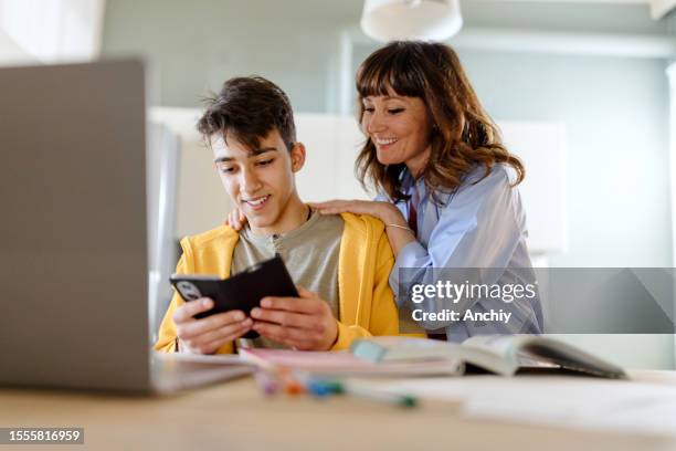 niño mostrando algo a su madre en un teléfono inteligente - madres con hijos fotografías e imágenes de stock