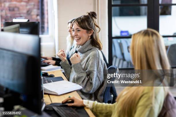 successful businesswoman sitting at desk with colleagues in office - blonde cheering stock-fotos und bilder