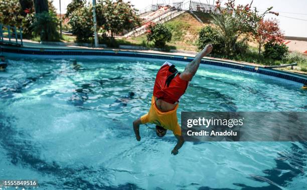 An amputee teenager dives into a pool during summer camp, organized by the Palestine Children's Aid Association, headquartered in USA, where amputee...
