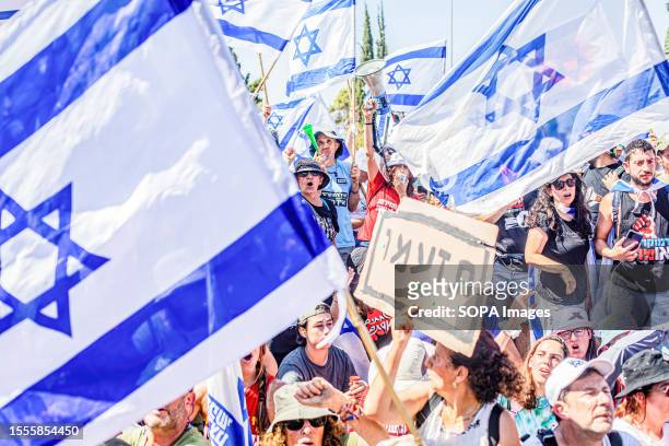 Protestors chant and gesture as another holds a sign that read in Hebrew: "be furious" during an anti-judicial overhaul demonstration out side the...