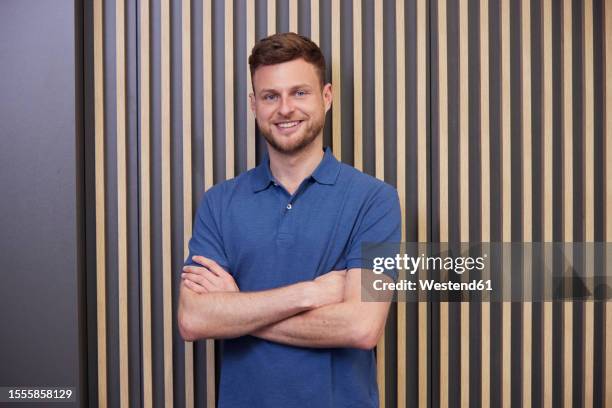 confident technician with arms crossed in front of wall - camisa de polo fotografías e imágenes de stock