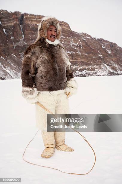 inuit man in fur jacket and pants & dog sled whip - inuit foto e immagini stock