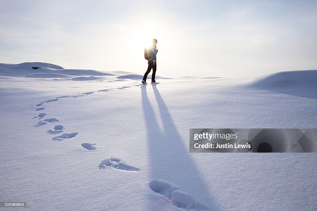 Girl walking on fresh snow with foot steps and sun