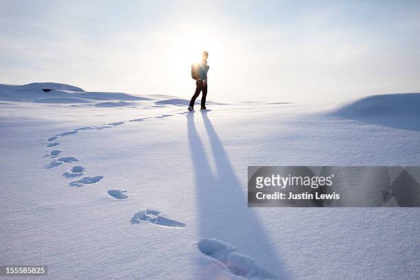 girl walking on fresh snow with foot steps and sun - footprint stock pictures, royalty-free photos & images