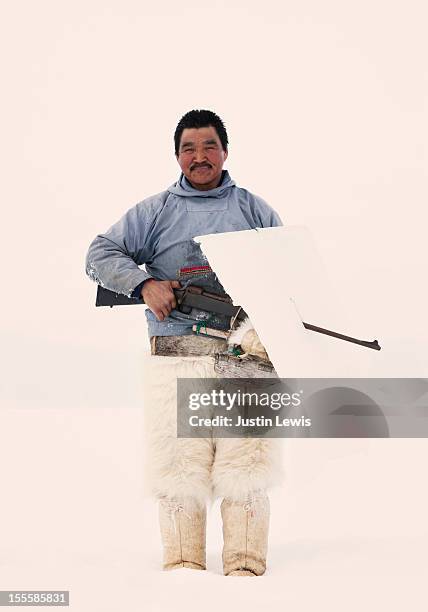 inuit man hold hunting gun in polar bear pants - qaanaaq stock pictures, royalty-free photos & images