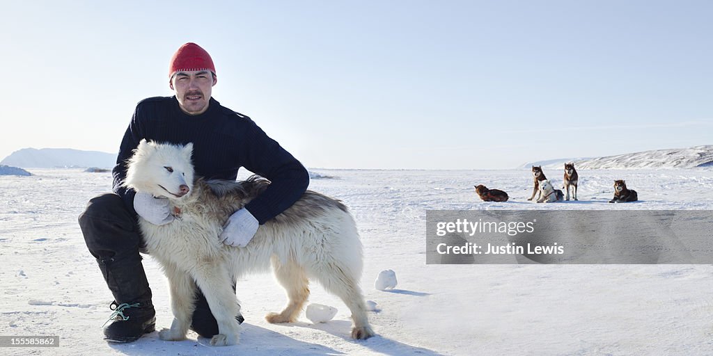Inuit man poses with arctic dog on sea ice