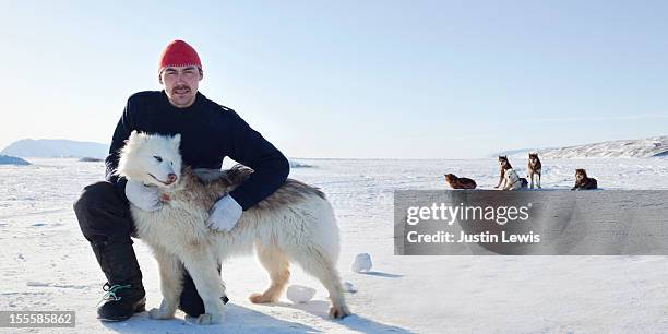 inuit man poses with arctic dog on sea ice - qaanaaq stock pictures, royalty-free photos & images