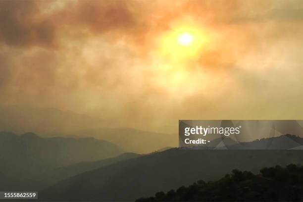 This image grab taken from AFPTV video footage shows smoke clouds covering the sky during wildfires in the forests of Bejaia in northern Algeria on...