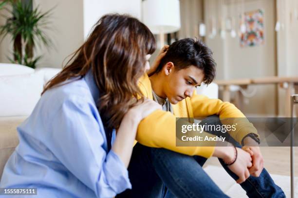 worried son talking about school bullying with his mother - parent stock pictures, royalty-free photos & images