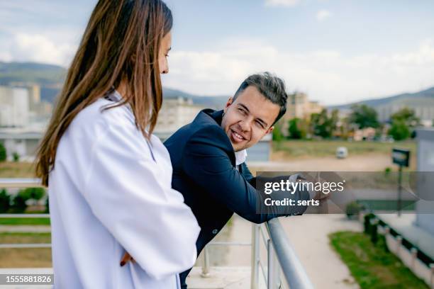 rooftop retreat: business executive and young female doctor taking a break and engaging in conversation - nurse flirting stock pictures, royalty-free photos & images