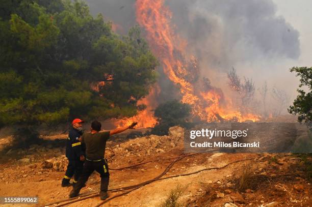 Locals help firefighters as they try to extinguish a wildfire burning near the village Vlyhada near Athens on July 19, 2023 in Athens, Greece....