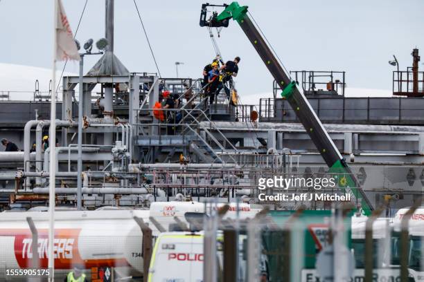 Climate activists are removed after climbing onto pipework as they protest at Grangemouth INEOS oil refinery on July 19, 2023 in Grangemouth,...
