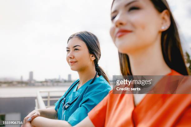 serenity on the terrace: portrait of two young female beautiful healthcare workers enjoying a relaxing break - community health centre stock pictures, royalty-free photos & images