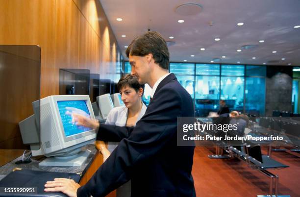 Office workers operate touch screen computer terminals in a reception area of the London Underwriting Centre, based at 3 Minster Court on Mincing...