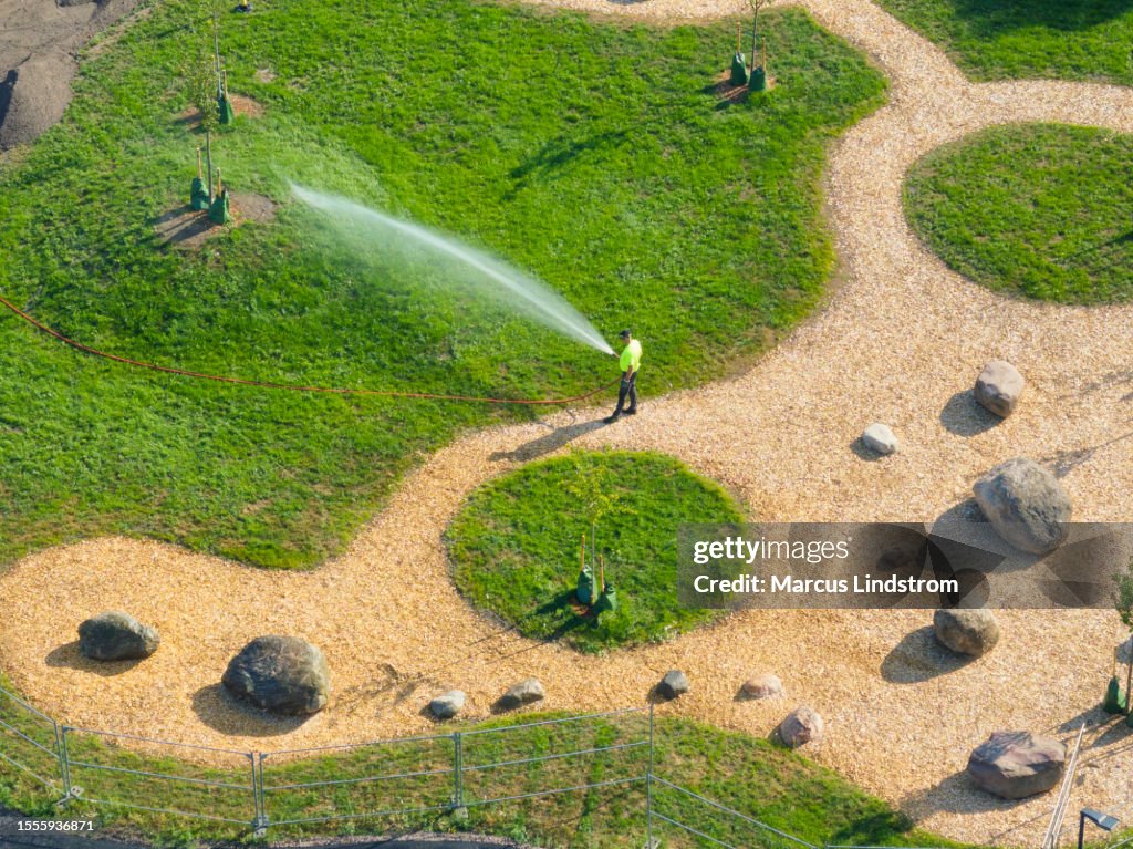 Homme arrosant la pelouse dans un parc