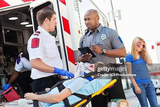 ambulance medic and police officer discussing accident scene - police rescue stock pictures, royalty-free photos & images