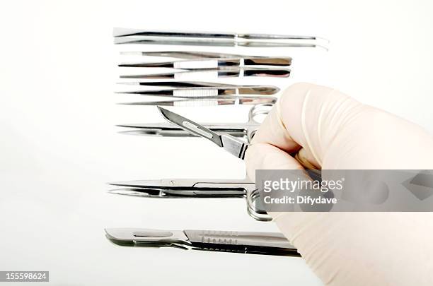 instrumentos quirúrgicos en el espejo con una mano sostiene escalpelo - fórceps fotografías e imágenes de stock