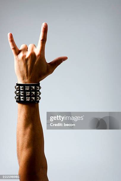 man in wristband making rock & roll hand symbol - rock hand stock pictures, royalty-free photos & images