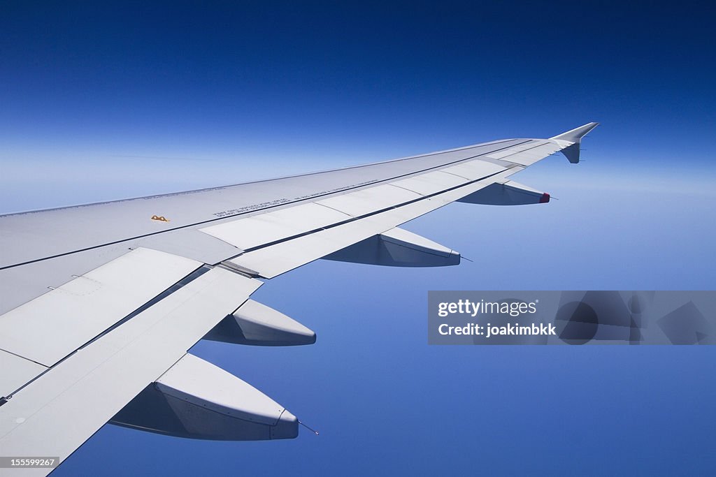 The wing of an airplane with a clear blue sky