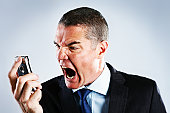 Absolutely furious businessman shouts into cell phone