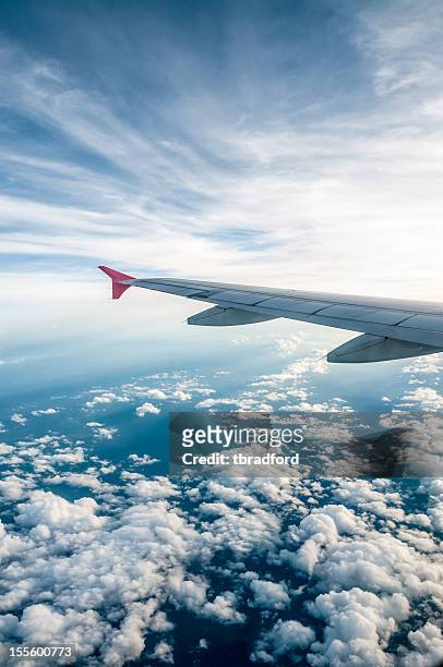 view of the cloudy sky and left airplane wing from a window - airplane wing stockfoto's en -beelden