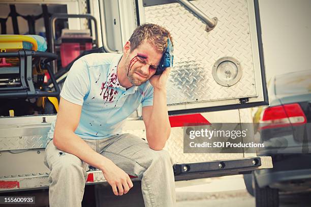 injured man with ice pack sitting on an ambulance - head wound stock pictures, royalty-free photos & images