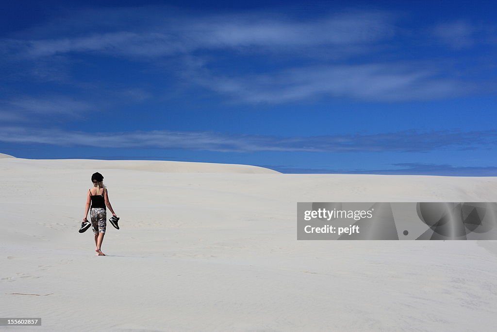 Chica caminando por el desierto de dunas de arena