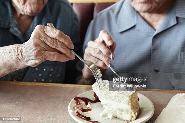 grandpa and grandma sharing cake - gâteau stockfoto's en -beelden
