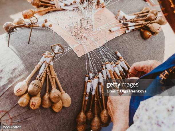 elderly woman weaves lace with bobbins at workshop. - mani fili foto e immagini stock