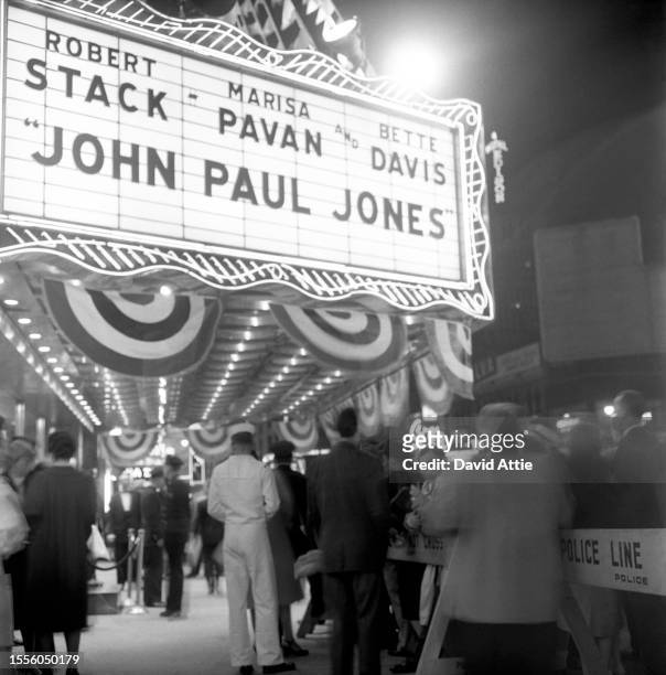 Crowds wait as police and a sailor idle outside the Rivoli Theater at 1620 Broadway for the world premiere of the movie "John Paul Jones," starring...