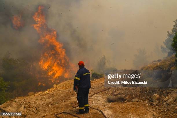 Firefighter runs so not to be surrounded by fire as he tries to extinguish a wildfire burning near the village Vlyhada near Athens on July 19, 2023...