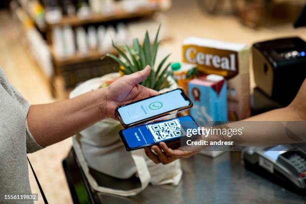frau, die im supermarkt mobil bezahlt - markt verkaufsstätte stock-fotos und bilder