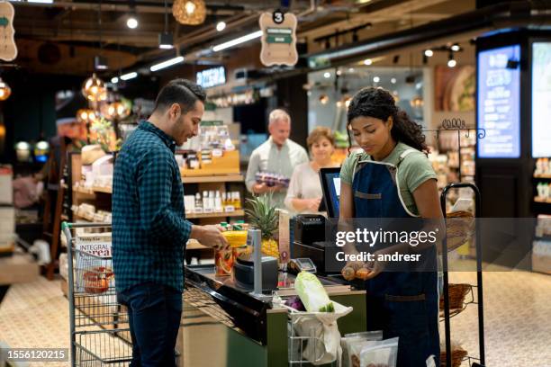 mann kauft im supermarkt ein und checkt an der kasse aus - black woman on cash register stock-fotos und bilder