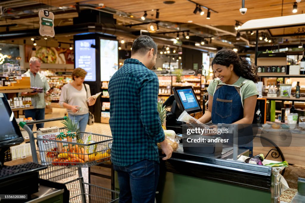 Happy cashier working at the supermarket registering products