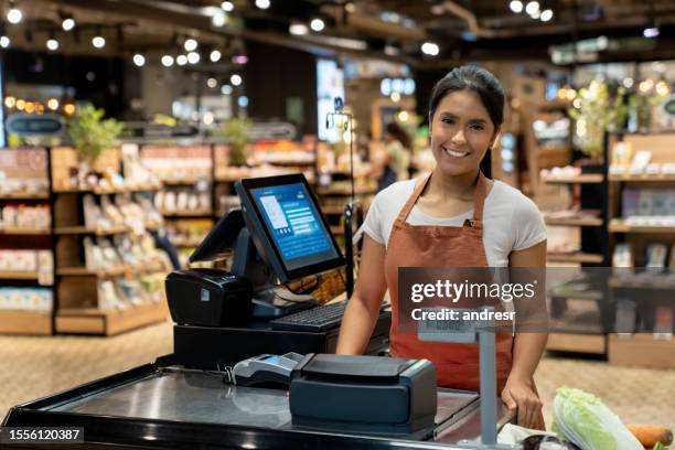 glückliche frau, die an der kasse in einem supermarkt arbeitet - markt verkaufsstätte stock-fotos und bilder