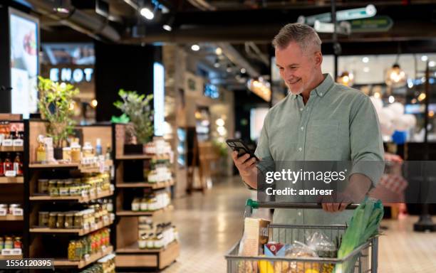 mann kauft lebensmittel im supermarkt und folgt einer einkaufsliste - supermarkt gang stock-fotos und bilder