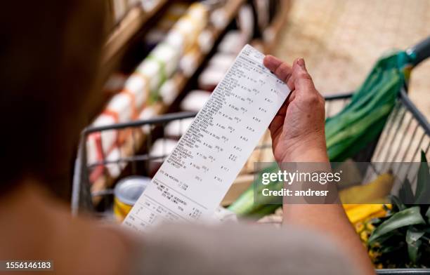 woman looking at a receipt after shopping at the supermarket - receipt 個照片及圖片檔