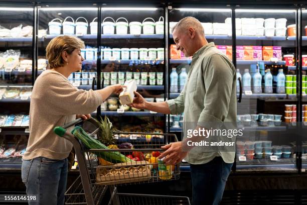 couple shopping at the supermarket and pointing at the expiration date of some milk - use by label stock pictures, royalty-free photos & images