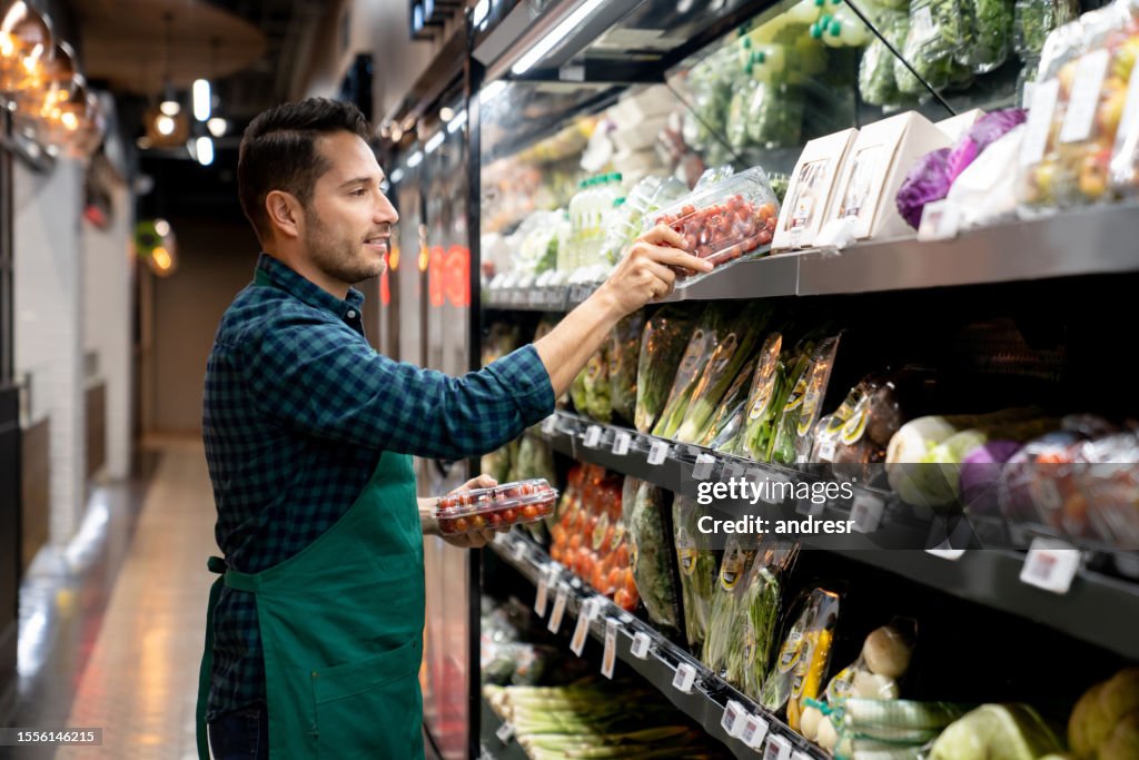 Retail clerk working at a supermarket restocking the produce aisle