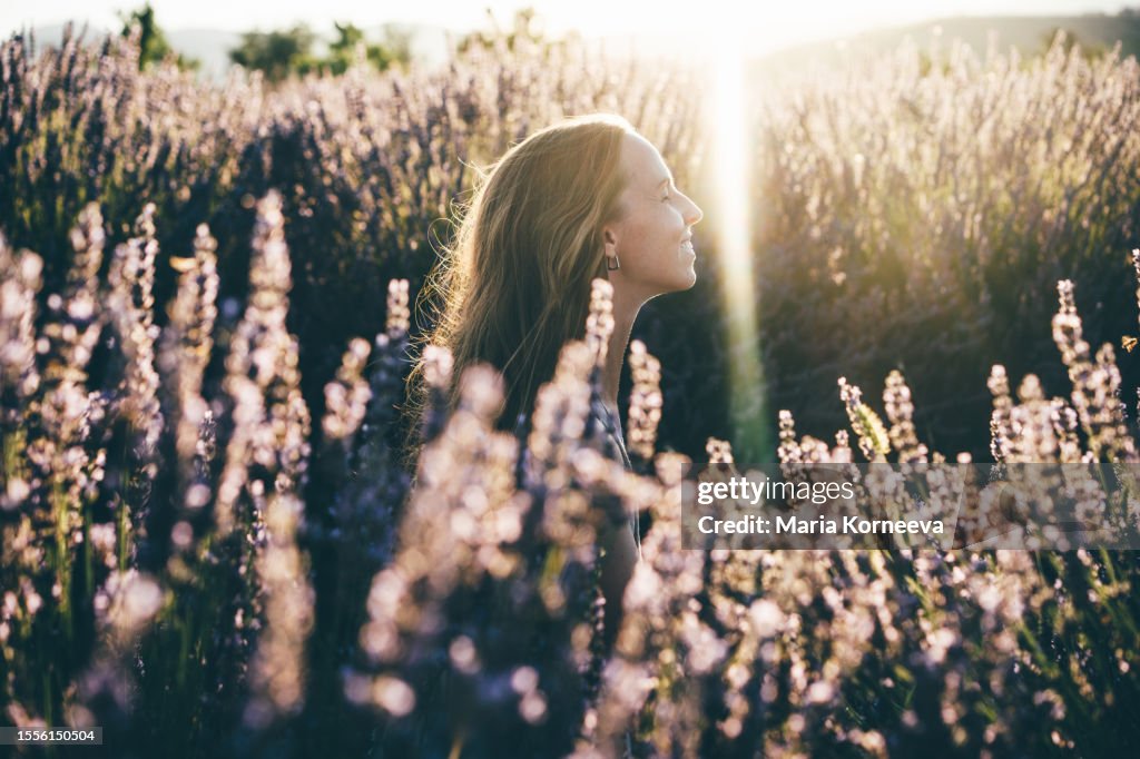 Photo of a smiling young woman in lavender field; enjoying the beautiful and peaceful weekend getaway.