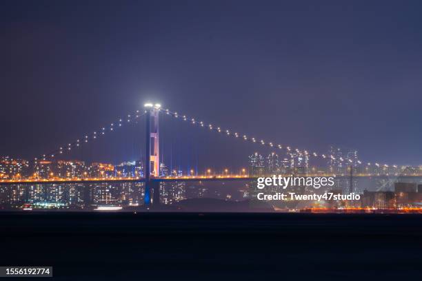 view of hong kong commercial port and stonecutters bridge at night - docklands studio stock pictures, royalty-free photos & images