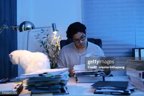 asian young businessman hands working on stacks of paperwork on his desk at home, work from home concept, business report, piles of unfinished documents, closeup view. - smart numbers office stockfoto's en -beelden