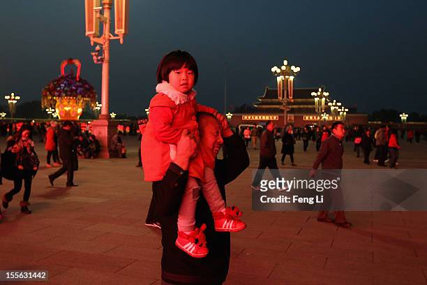 Chinese man carries a little girl at Tiananmen Square on November 6, 2012 in Beijing, China. The18th National Congress of the Communist Party of...