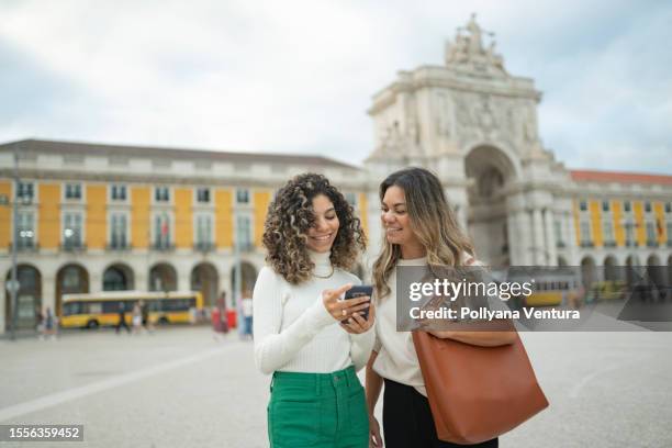 female friends using smartphone at praça do comércio in lisbon - 33 arches stock pictures, royalty-free photos & images