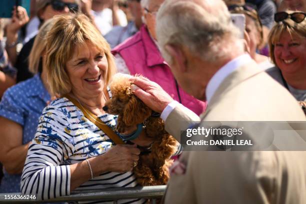 Britain's King Charles III pets a dog as he greets members of the public upon arrival at the Sandringham Flower Show, in Sandrigham, north west...