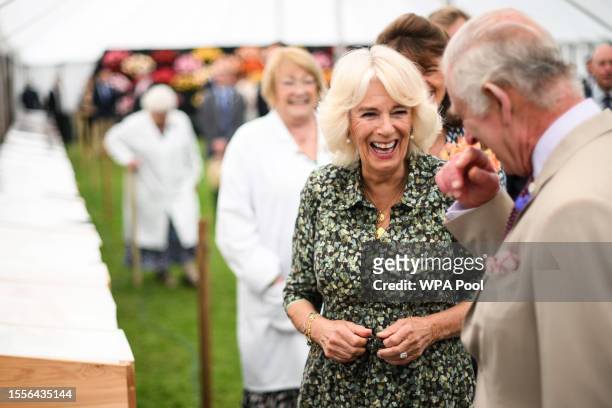 King Charles III and Queen Camilla laugh during a visit to the Sandringham Flower Show at Sandringham House on July 26, 2023 in King's Lynn, England.