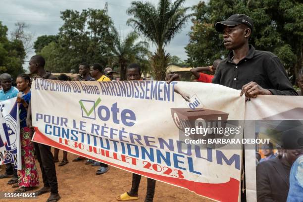 Supporters of the ruling United Hearts Movement party hold a banner urging people to vote yes for the upcoming referendum in a district of Bangui, on...