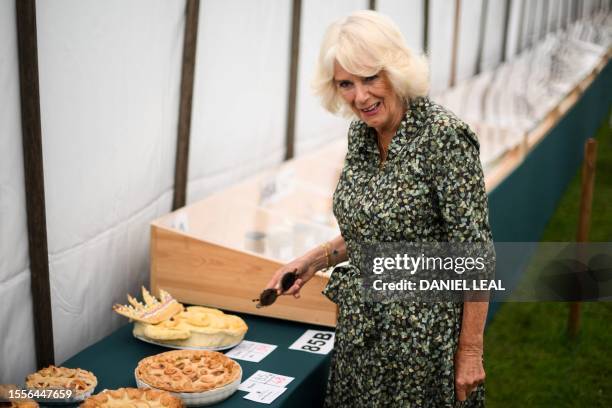 Britain's Queen Camilla reacts as she looks at a cake depicting Britain's King Charles III during a visit of the Sandringham Flower Show, in...